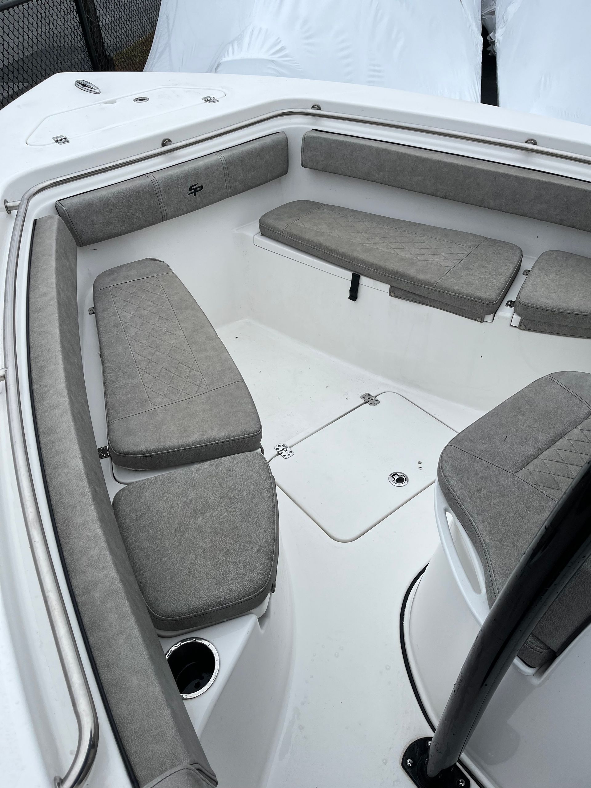 Interior view of a white boat with gray cushioned seats and a console with a steering wheel.