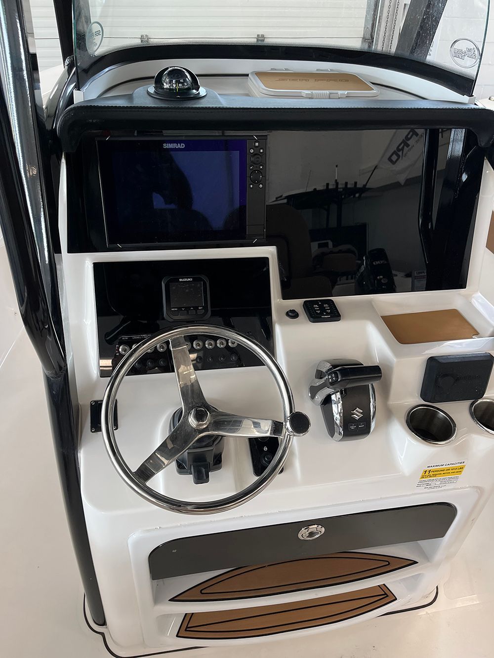 The cockpit of a boat with a steering wheel and a monitor.