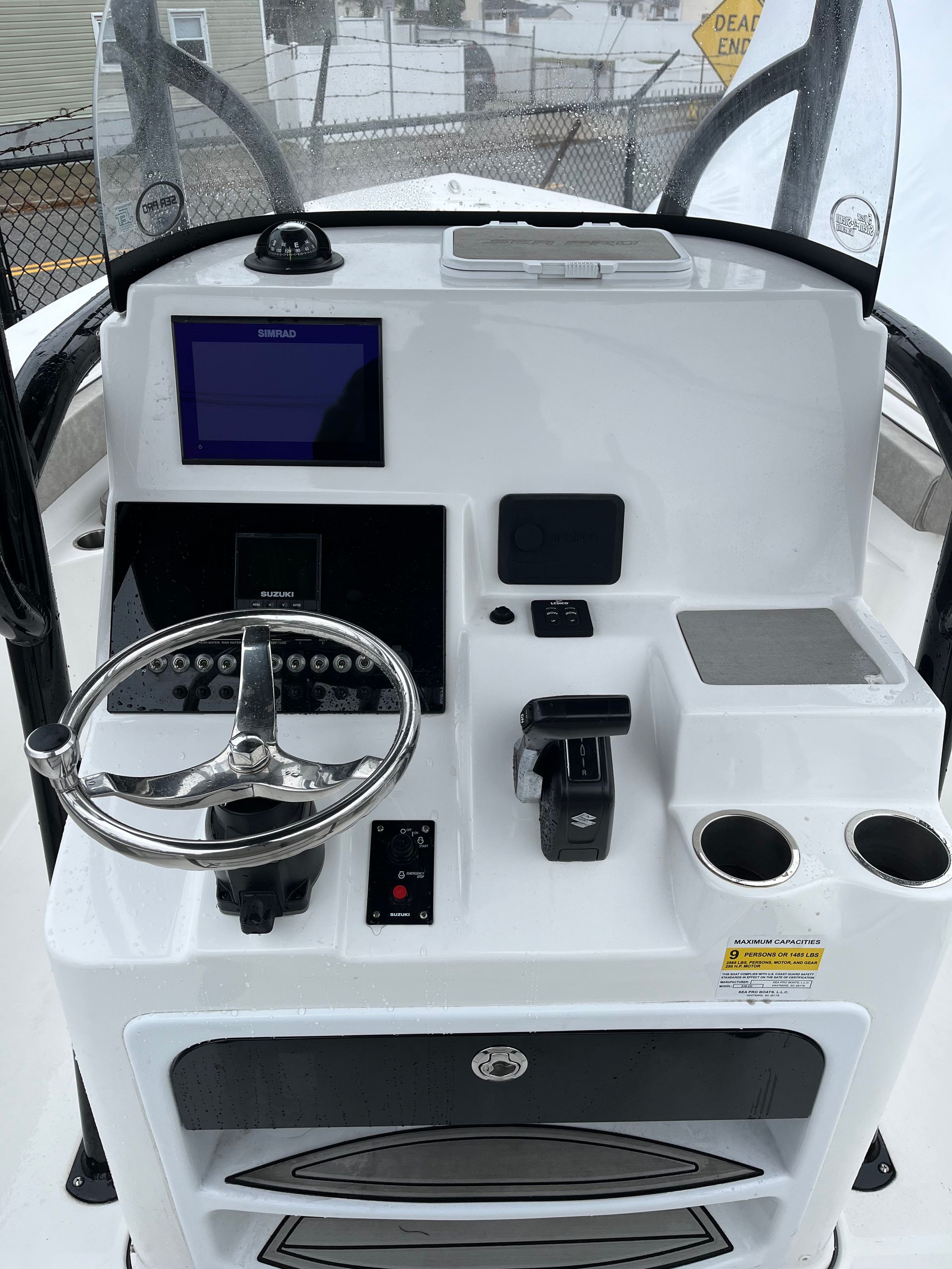White boat console with wheel, screen, gauges, and cup holders. Black frame.