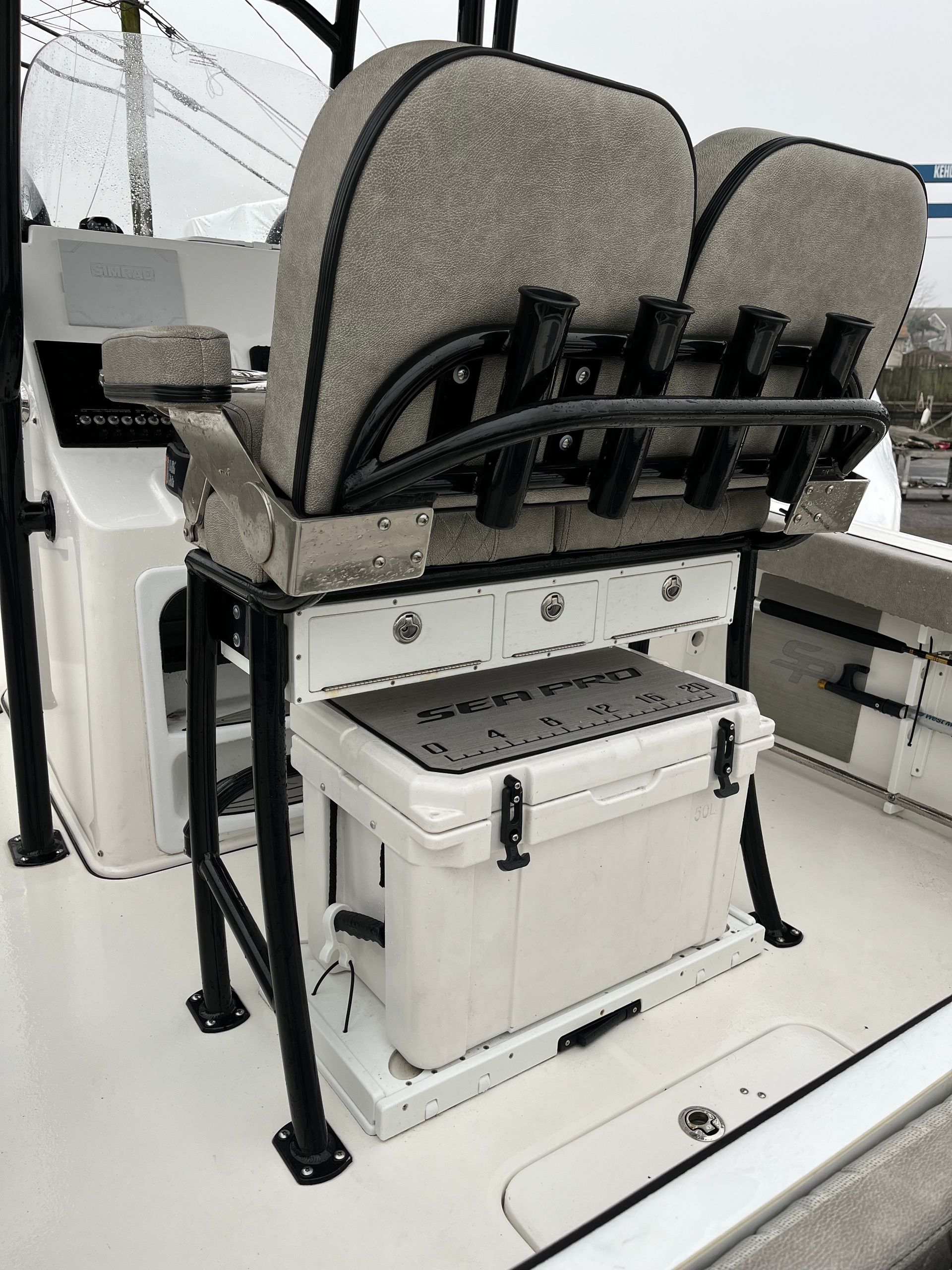 Boats helm seat with backrest, rod holders, and a cooler. White and gray colors are dominant.