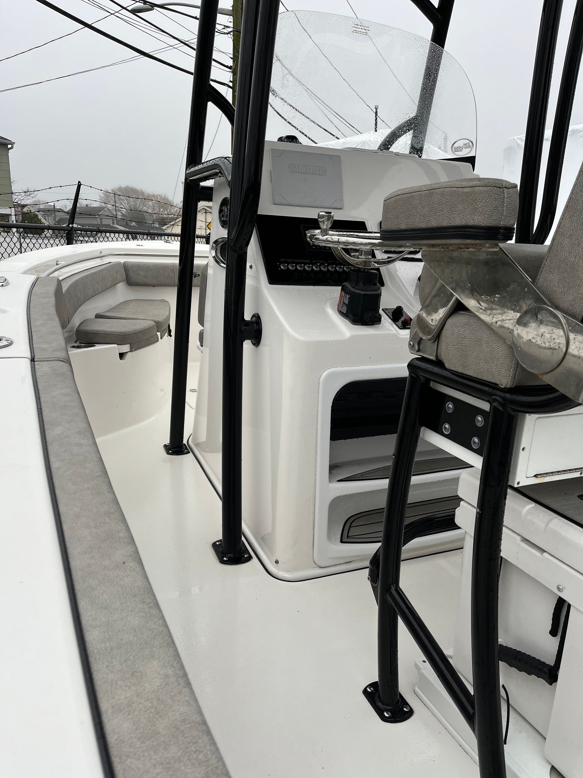 Interior of a white boat with gray seating and black support beams. The helm is central.