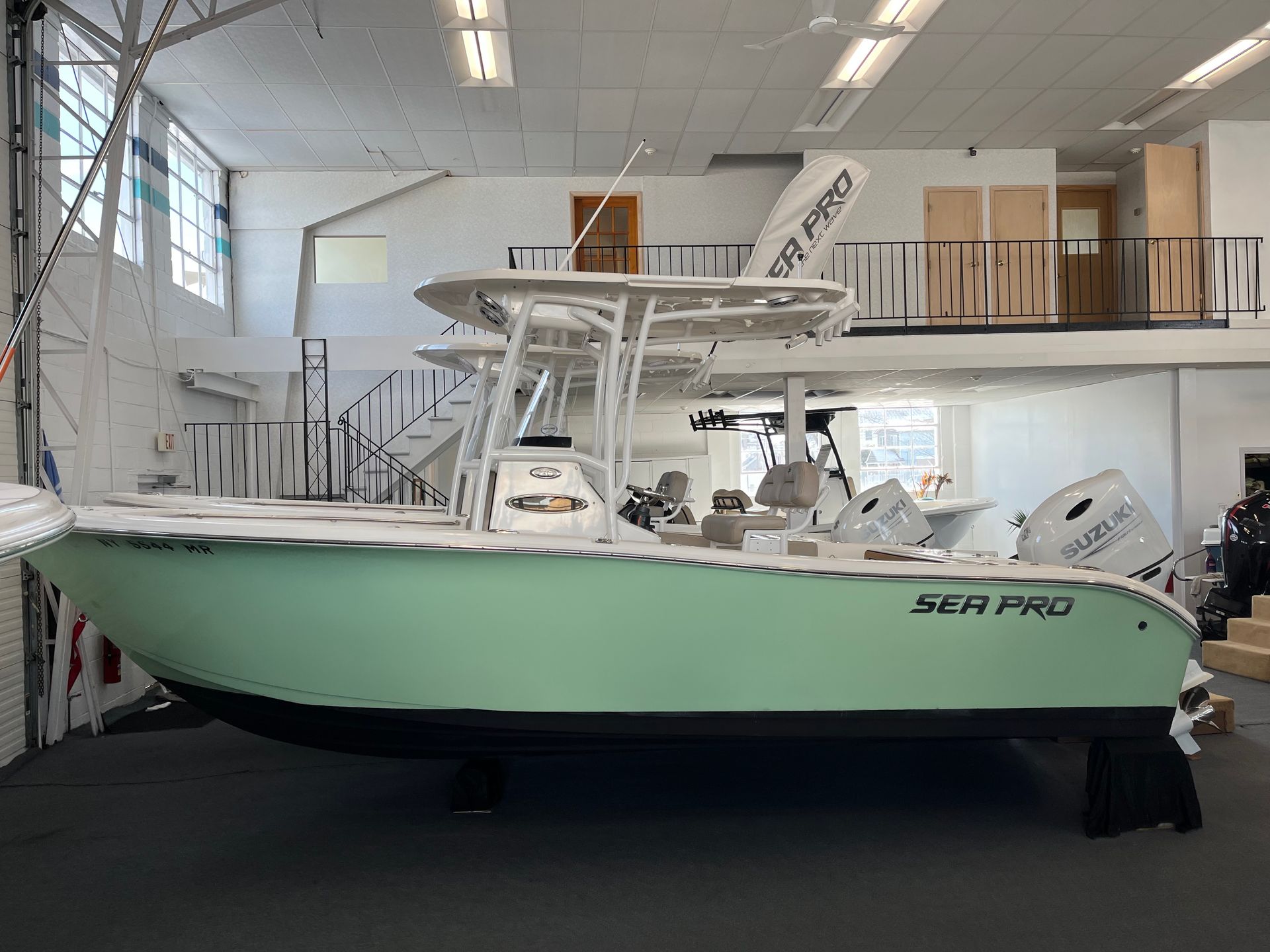 A light green Sea Pro boat inside a building. White upper structure, gray motor.