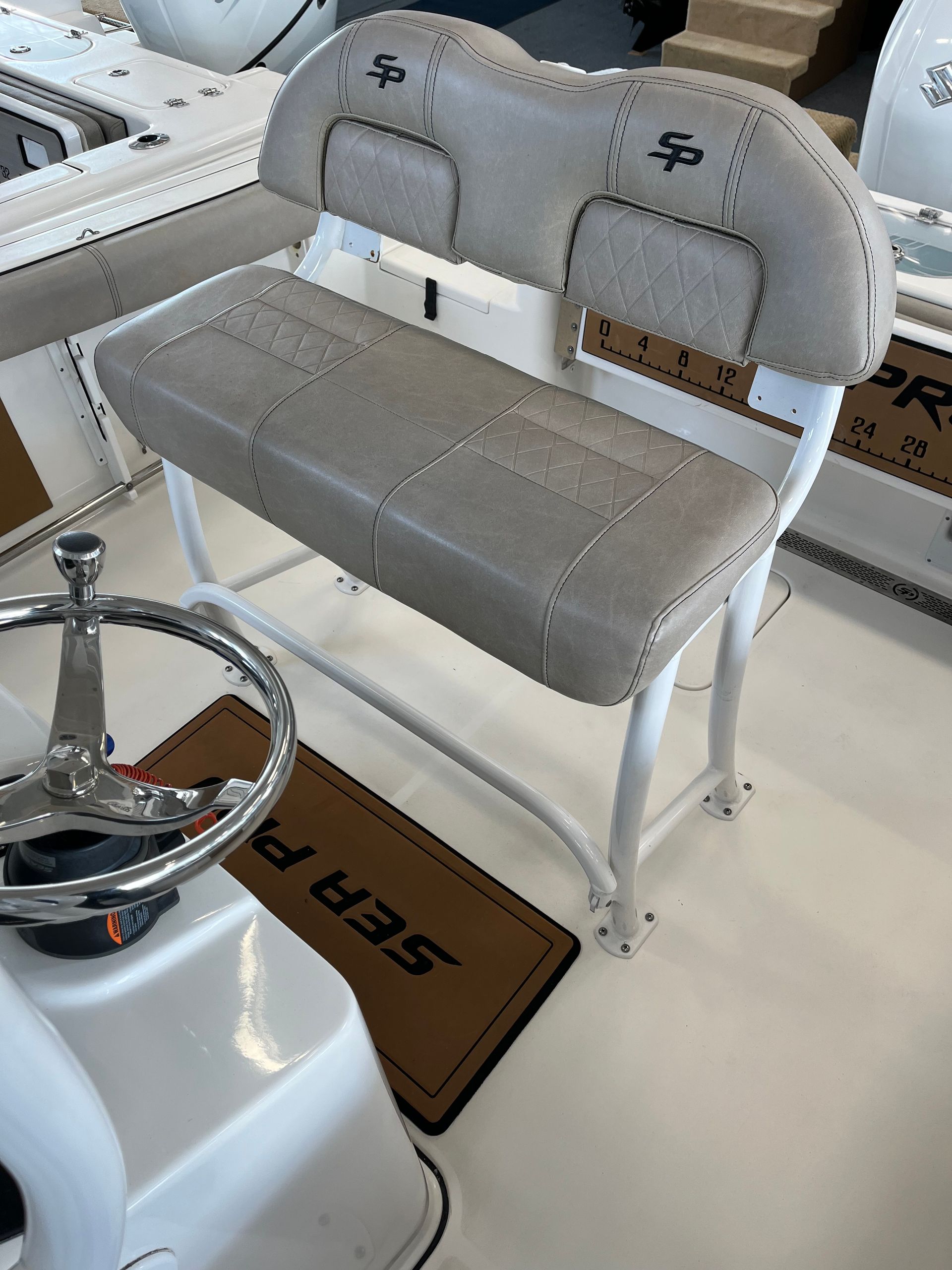 Boat helm seat with tan cushions and white frame.