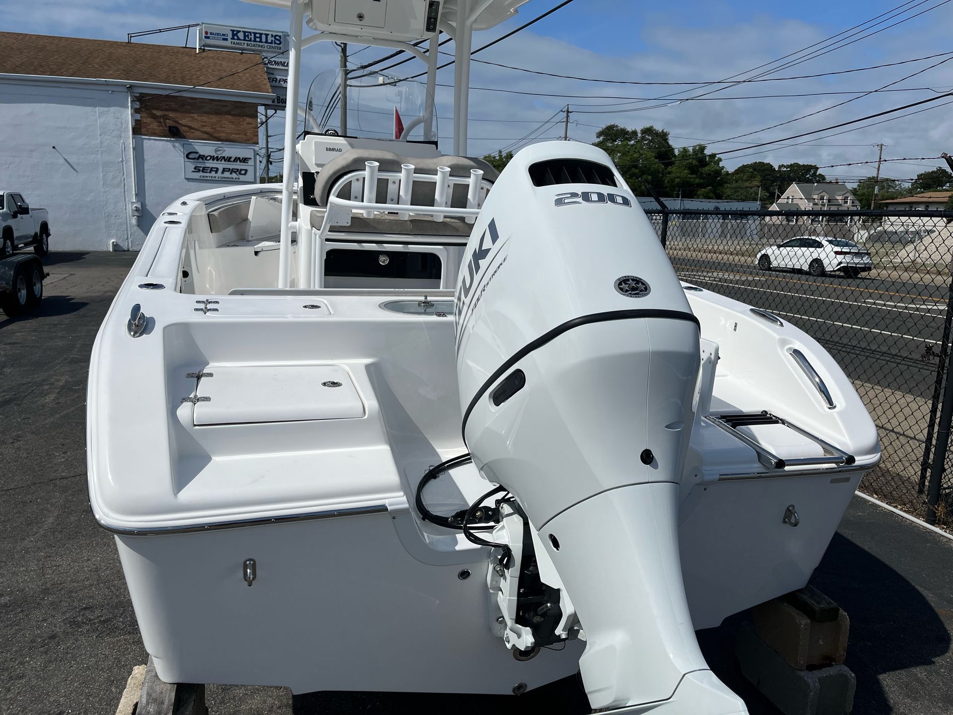 A white boat with a Suzuki outboard motor is parked in a parking lot