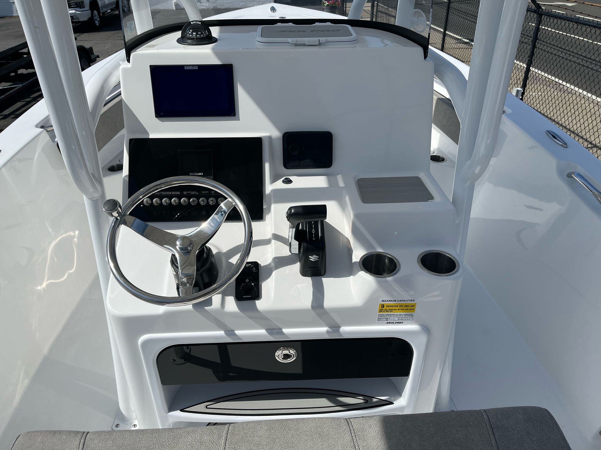 The front of a white boat with a steering wheel and a monitor