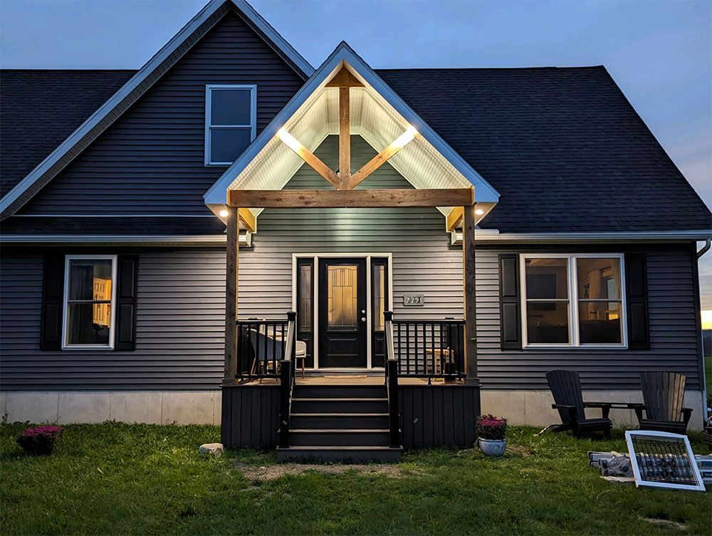 A house with a porch and stairs is lit up at night.
