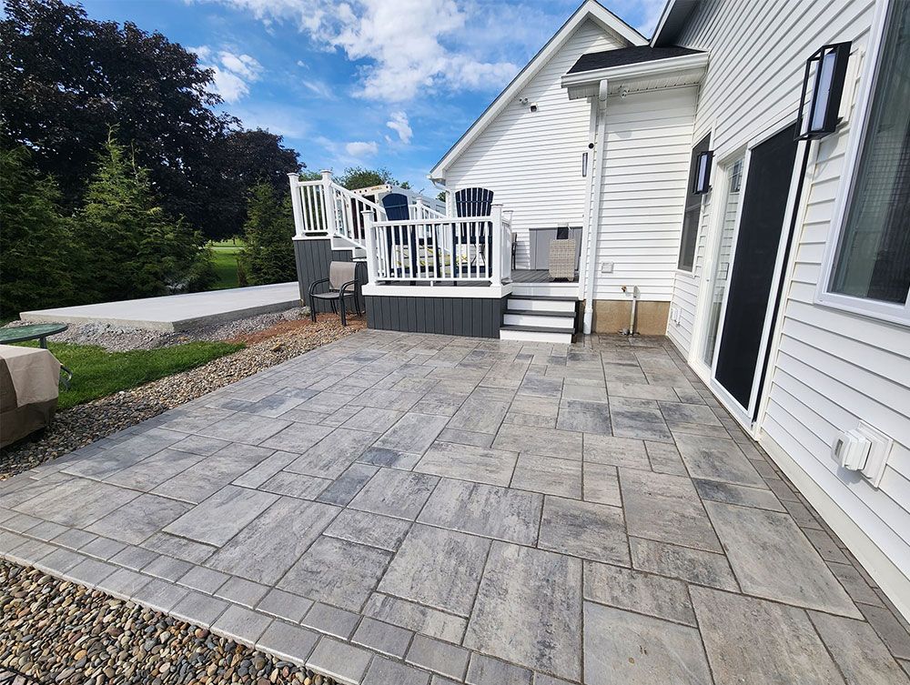 A patio with a deck and stairs in front of a white house.