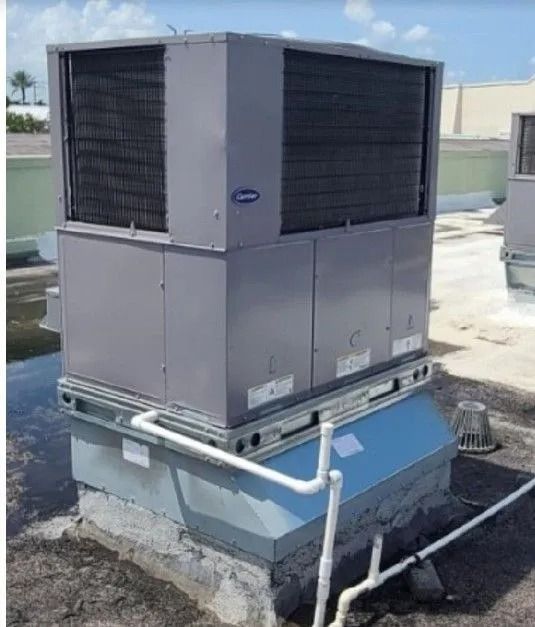 Rooftop HVAC unit, gray and blue, with piping. Carrier brand. Sunny, exterior setting.