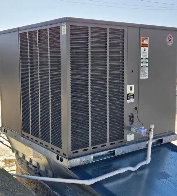 Gray rooftop HVAC unit with a visible metal grille, vents, and a white pipe.