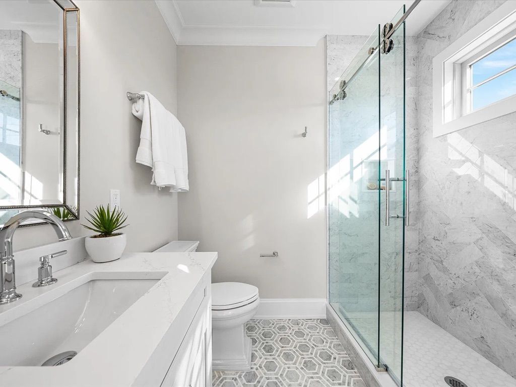 A bathroom with a toilet, sink, mirror, and walk in shower.