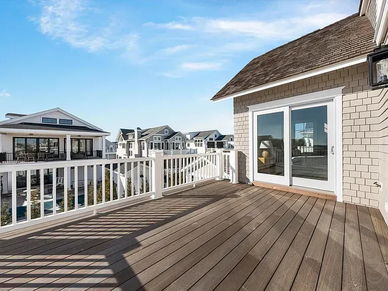 There is a large deck with a white railing and sliding glass doors.