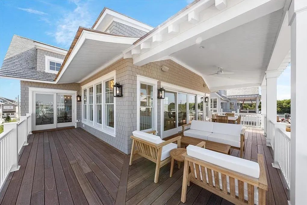 A large deck with a couch and chairs on it in front of a house.