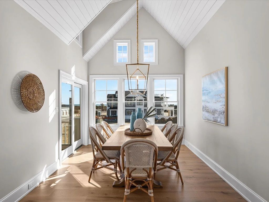 A dining room with a long table and chairs and a vaulted ceiling.