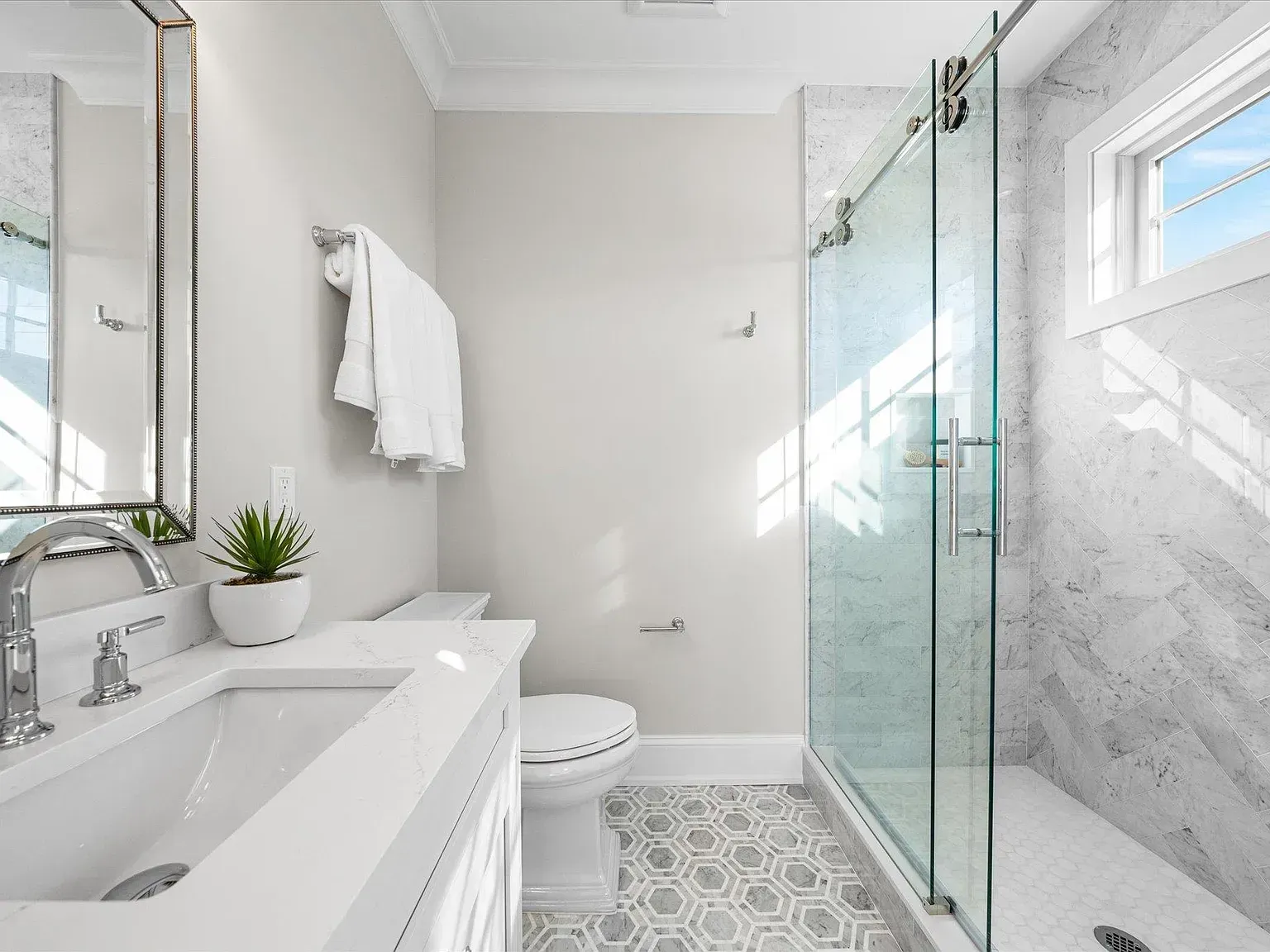 A bathroom with a toilet, sink, mirror, and walk in shower.