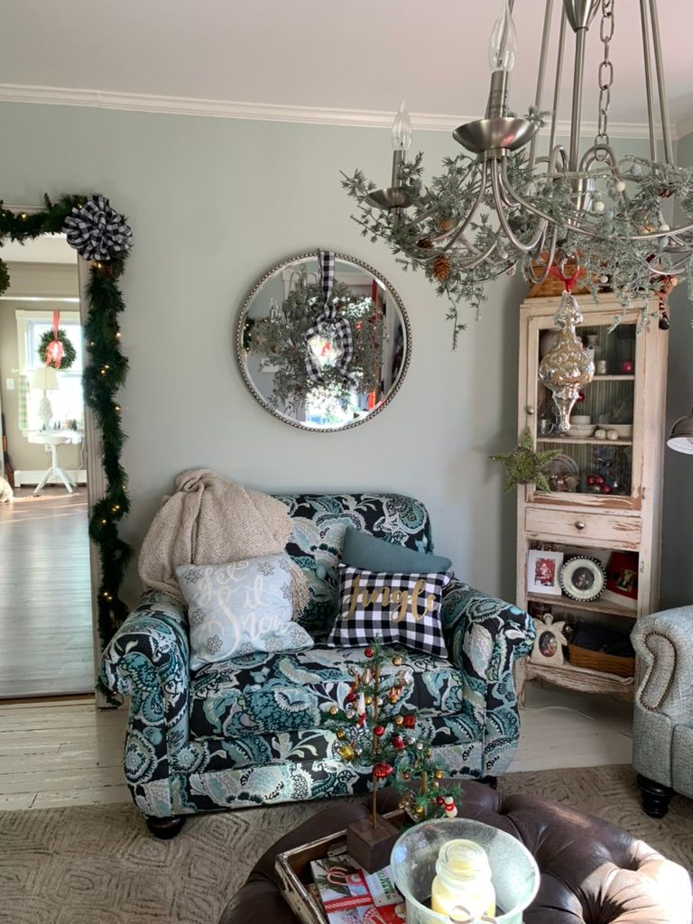 A living room with a couch, chair, coffee table, mirror, and chandelier.