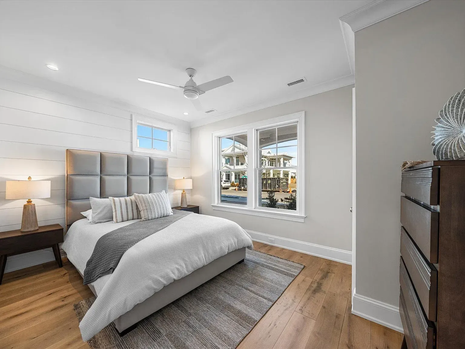 A bedroom with a bed, dresser, nightstand, and ceiling fan.