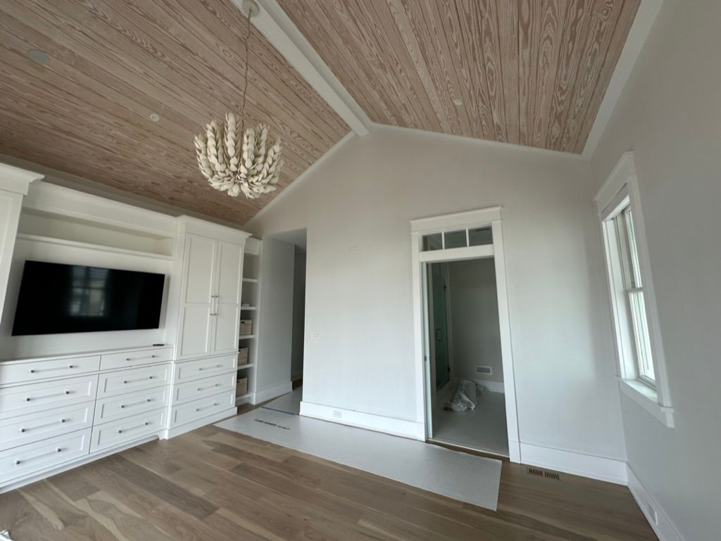A living room with a vaulted ceiling, hardwood floors, a flat screen TV, and a chandelier.