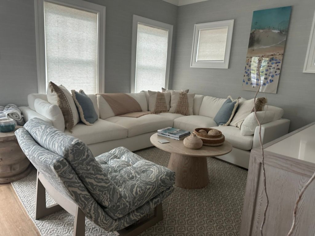 A living room with a large sectional couch, chair, coffee table, and ottoman.