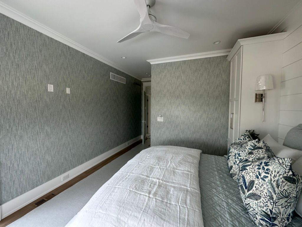 A bedroom with a large bed and a ceiling fan