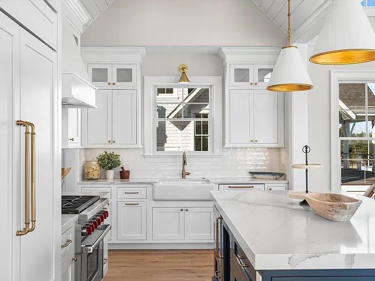 A kitchen with white cabinets, a stove, a sink, and a large island.