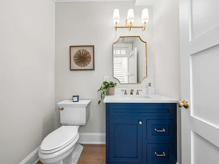 A bathroom with a toilet, sink, and mirror.