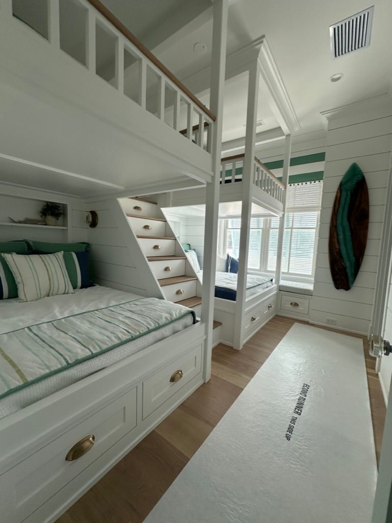 A bedroom with bunk beds and a surfboard on the wall.