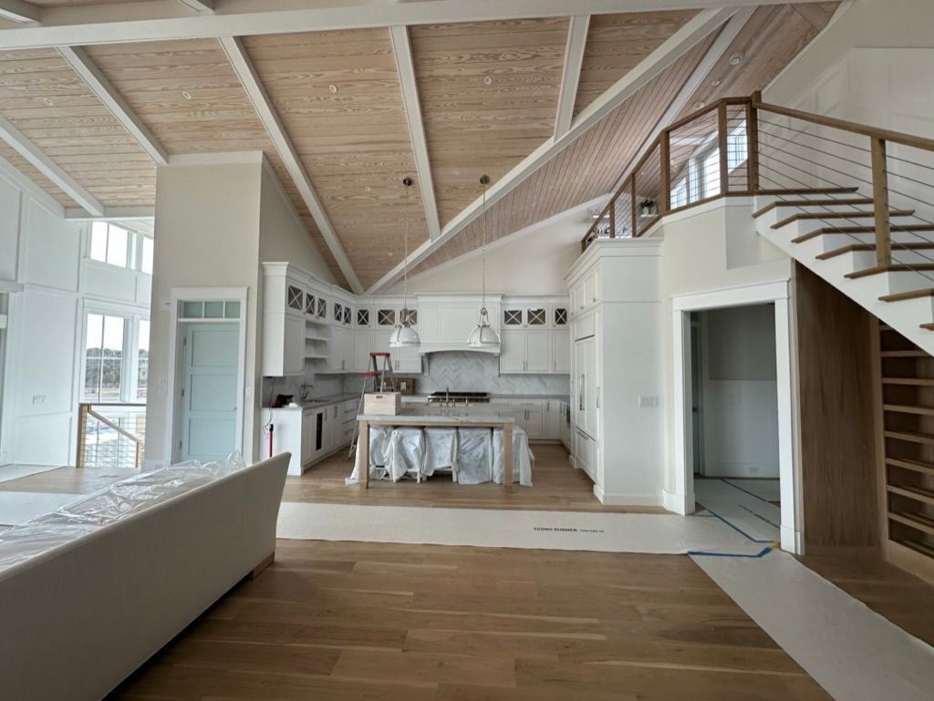 A large room with a staircase leading to the second floor and a kitchen.