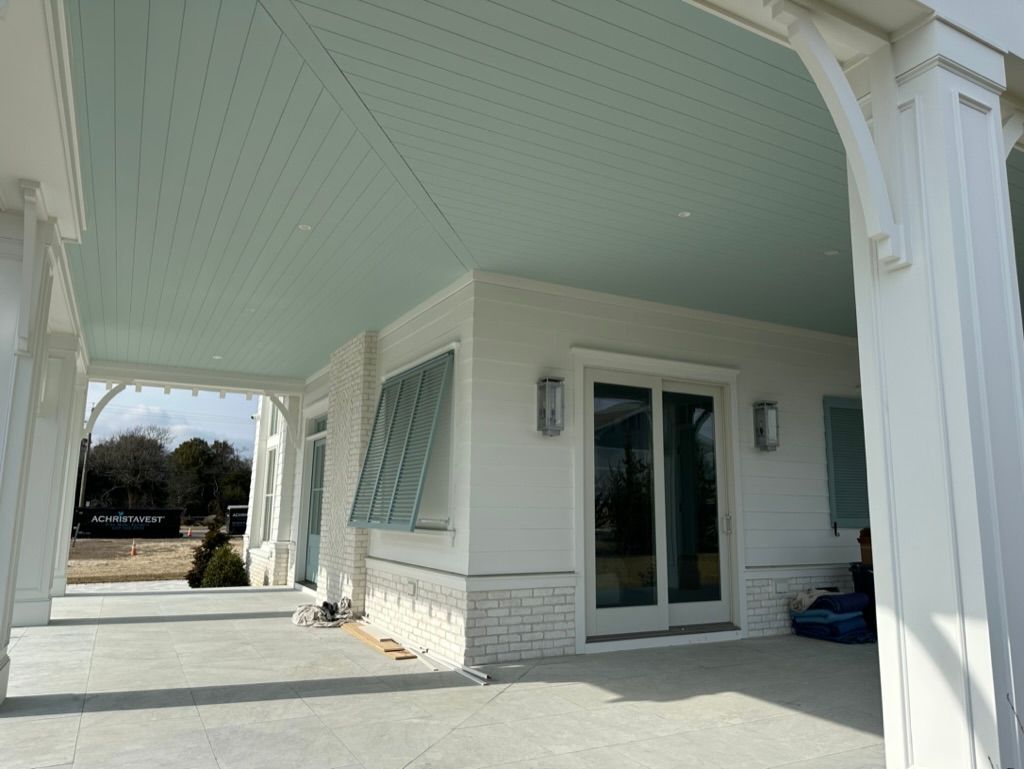 A white house with a blue ceiling and sliding glass doors
