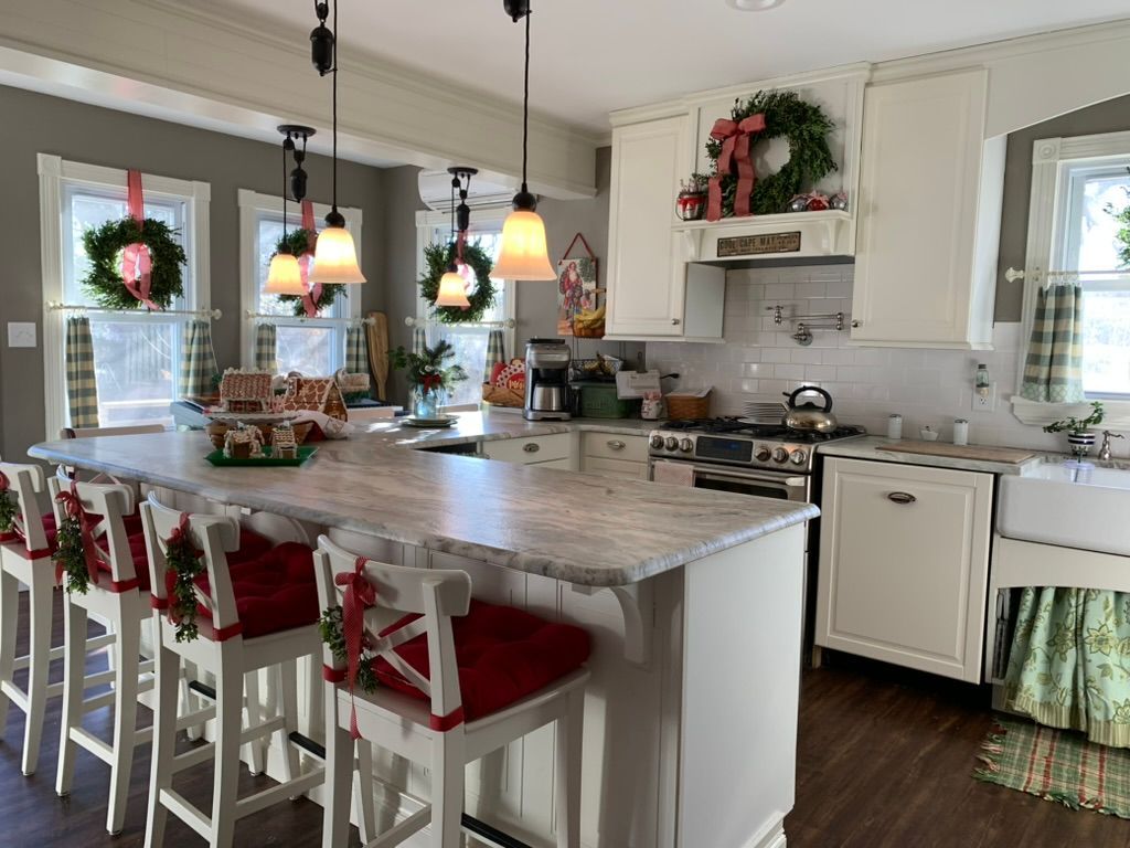 A kitchen with a large island and stools decorated for christmas.