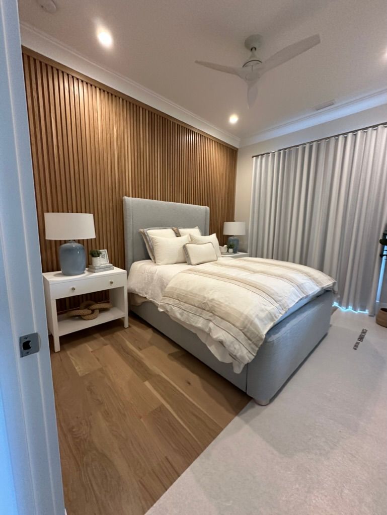 A bedroom with a bed, nightstand, lamps, and a ceiling fan.