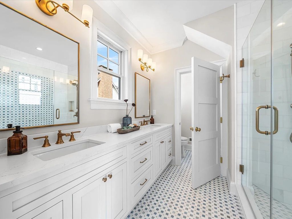A bathroom with two sinks, two mirrors, and a walk-in shower.