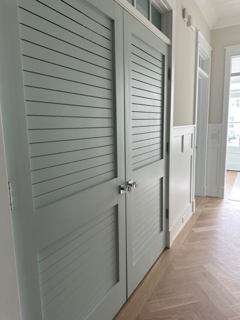 A hallway with shuttered doors and a wooden floor