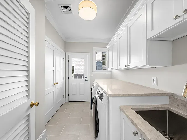 A laundry room with white cabinets, a washer and dryer, and a sink.
