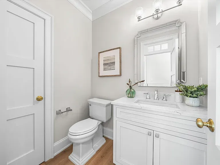 A bathroom with a toilet, sink, and mirror.