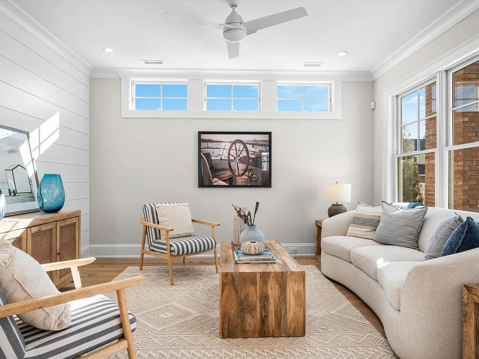 A living room with a couch, chairs, a coffee table, and a ceiling fan.
