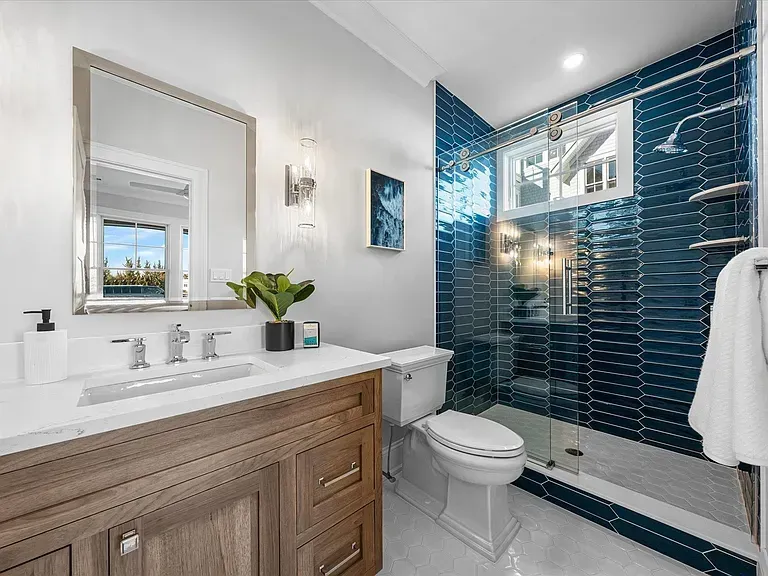 A bathroom with a toilet, sink, mirror, and shower.