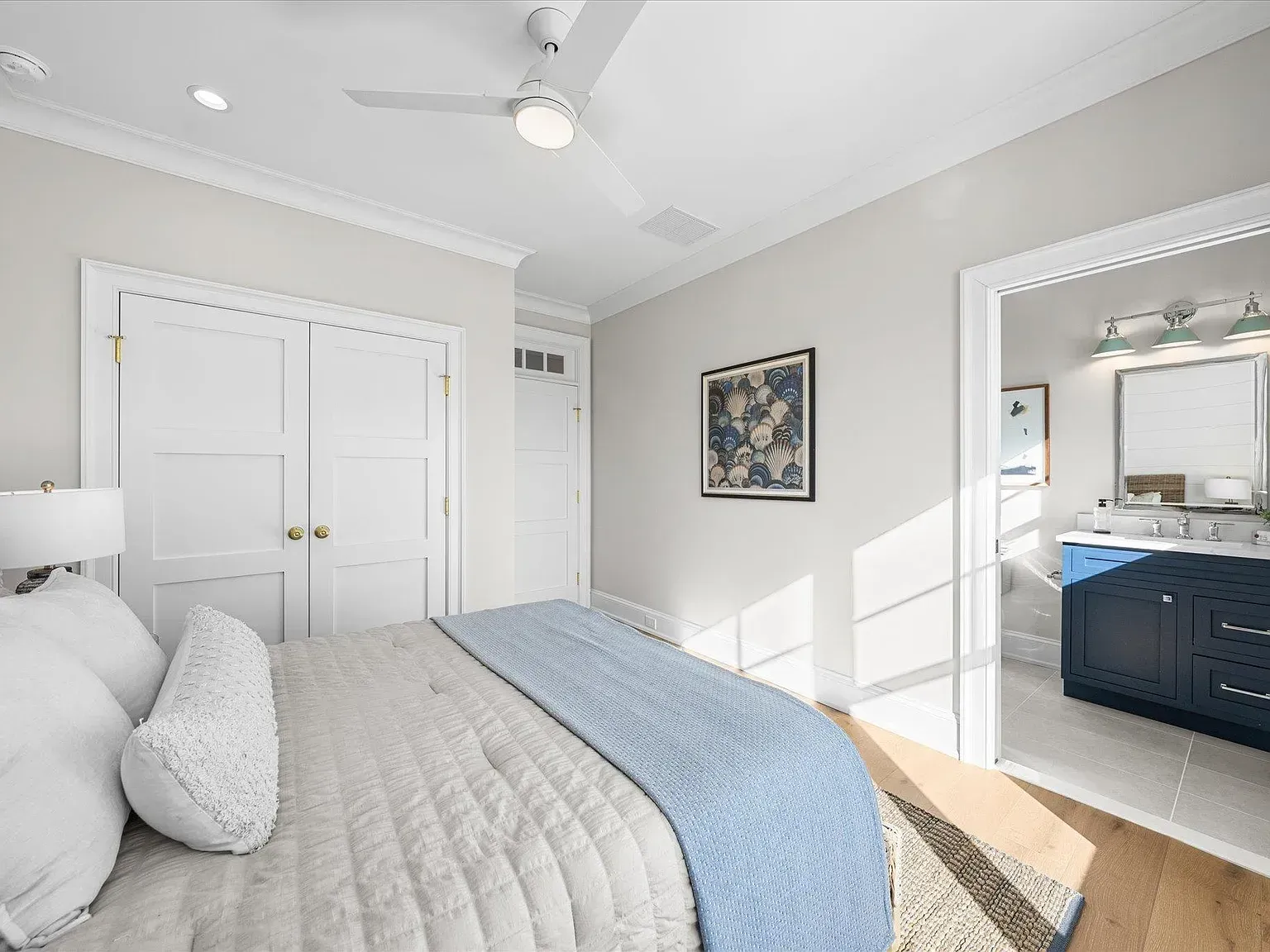 A bedroom with a bed, ceiling fan, and bathroom.