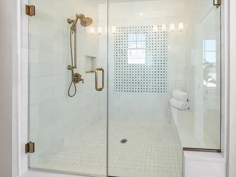 A bathroom with a walk in shower with a glass door.