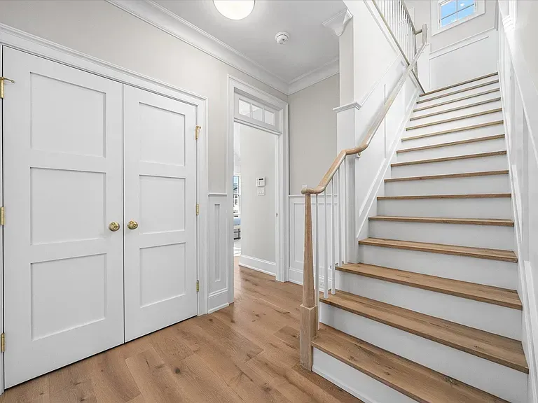 A hallway with white doors and wooden stairs in a house.