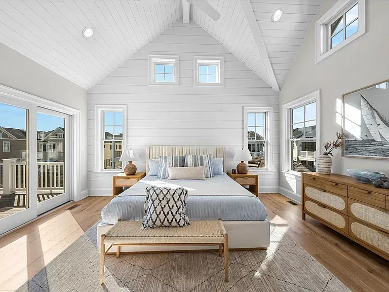 A bedroom with a large bed and lots of windows.