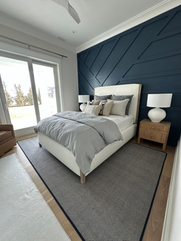 A bedroom with a bed, nightstand, lamps, and a blue wall.