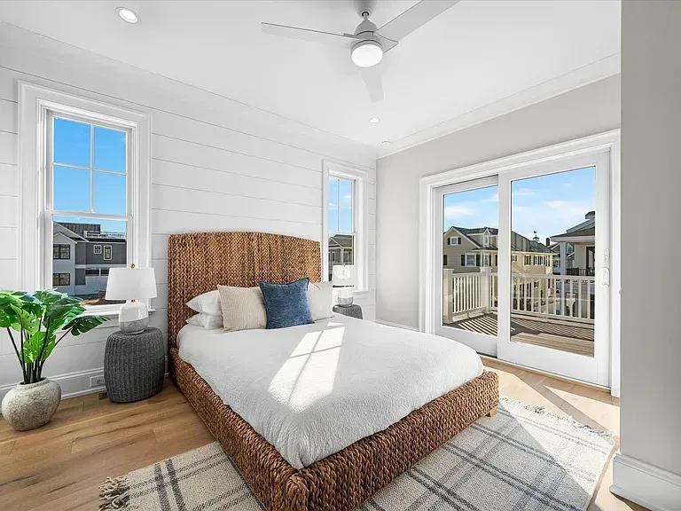 A bedroom with a bed, ceiling fan, and sliding glass doors.