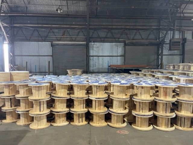 A bunch of wooden spools are stacked on top of each other in a warehouse