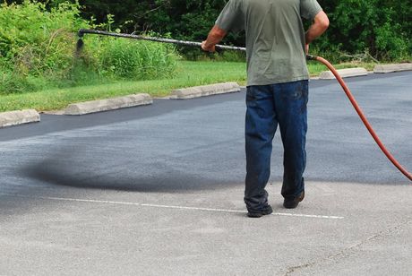 A man is spraying asphalt with a hose