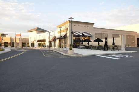 An empty parking lot in front of a building with tables and umbrellas