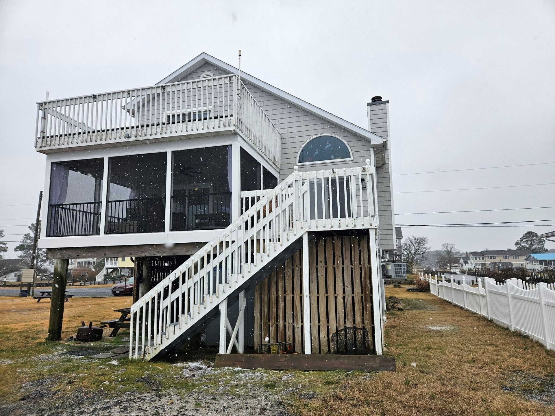 A large white house with a screened in porch and stairs.