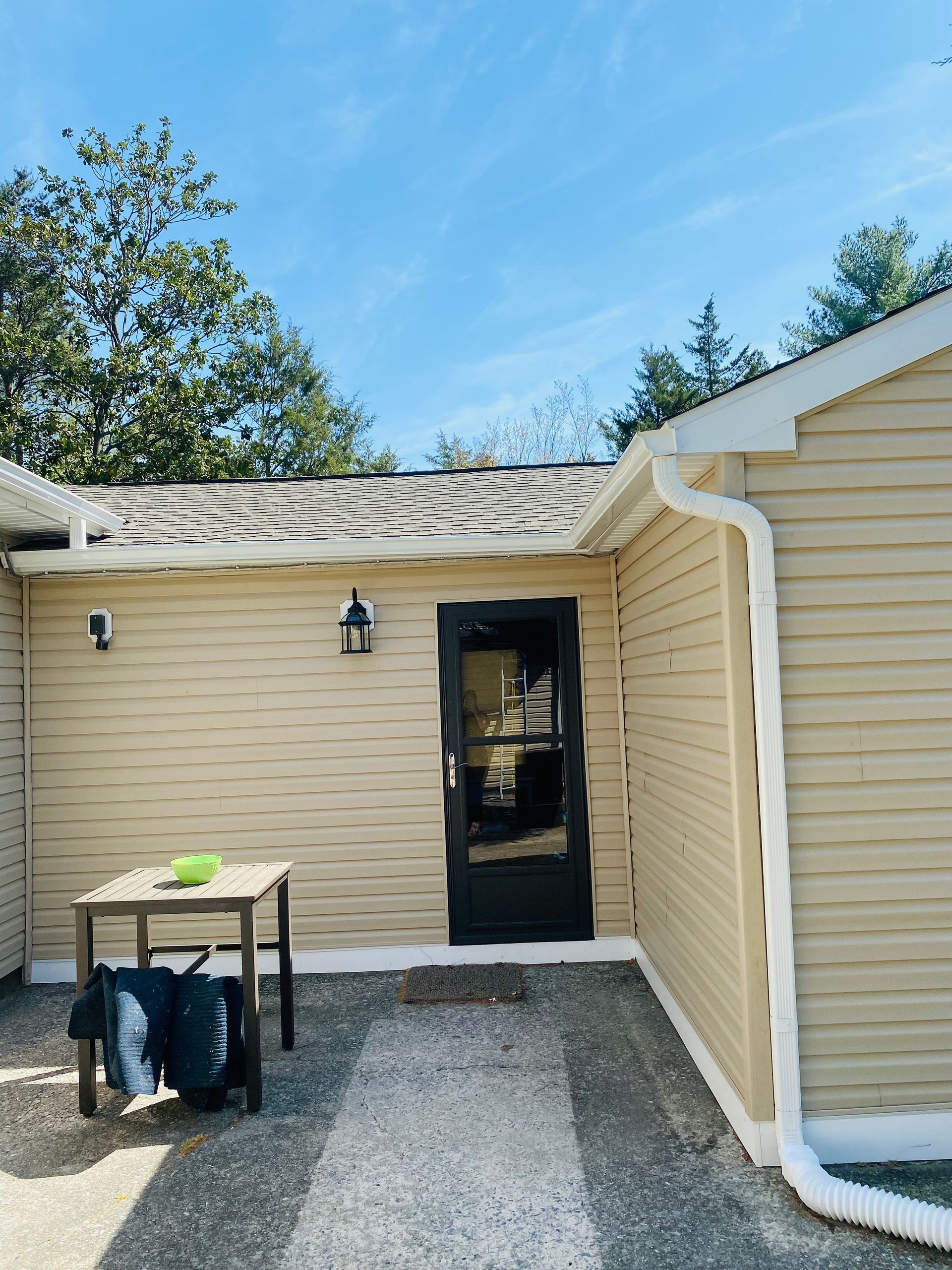A beige house with a black door and a table in front of it.