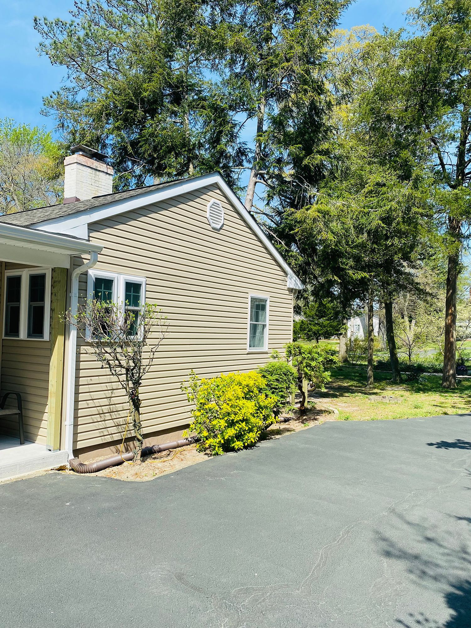 A small house with a driveway and trees in the background.