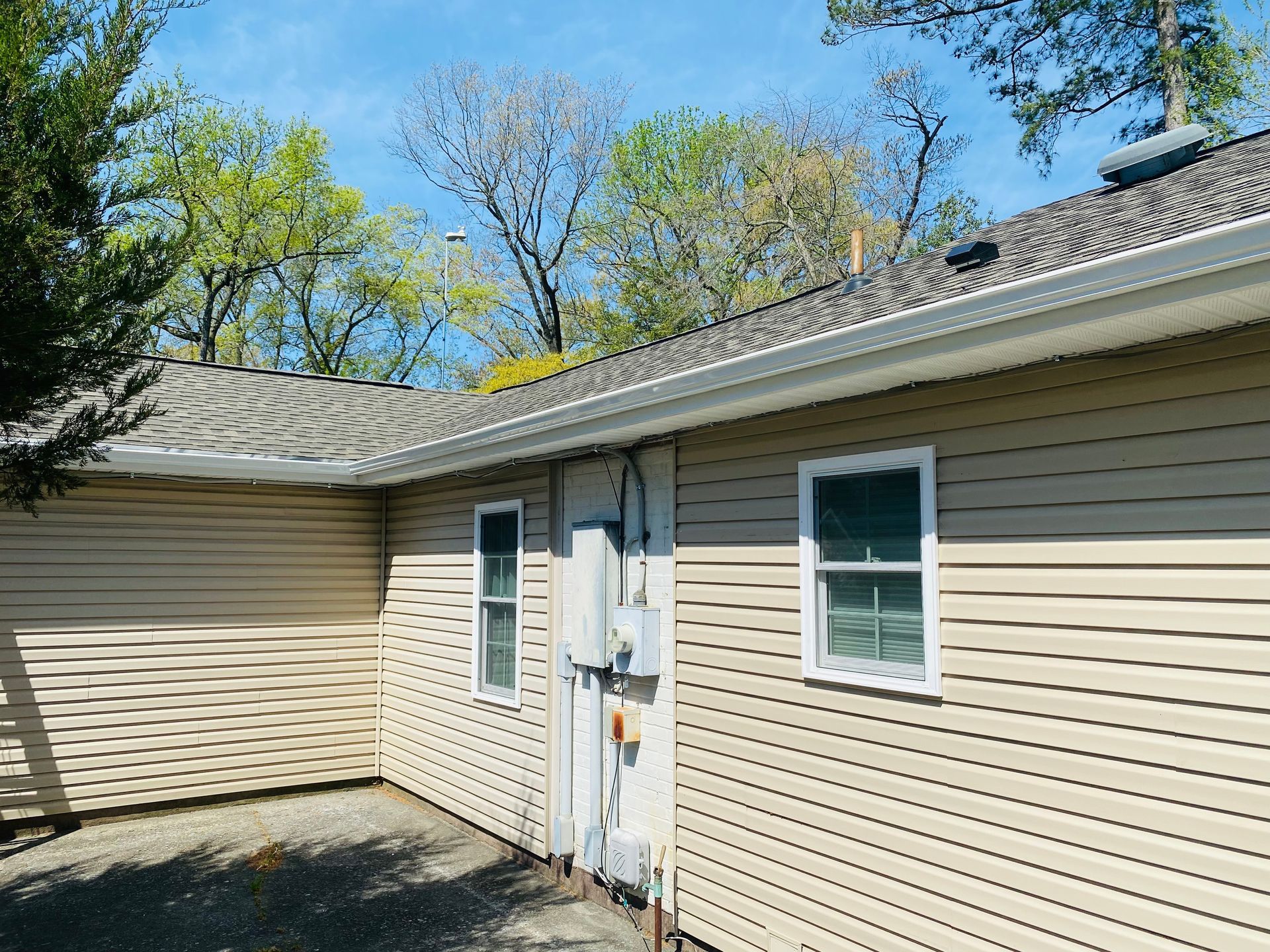 The back of a house with a lot of windows and a roof.