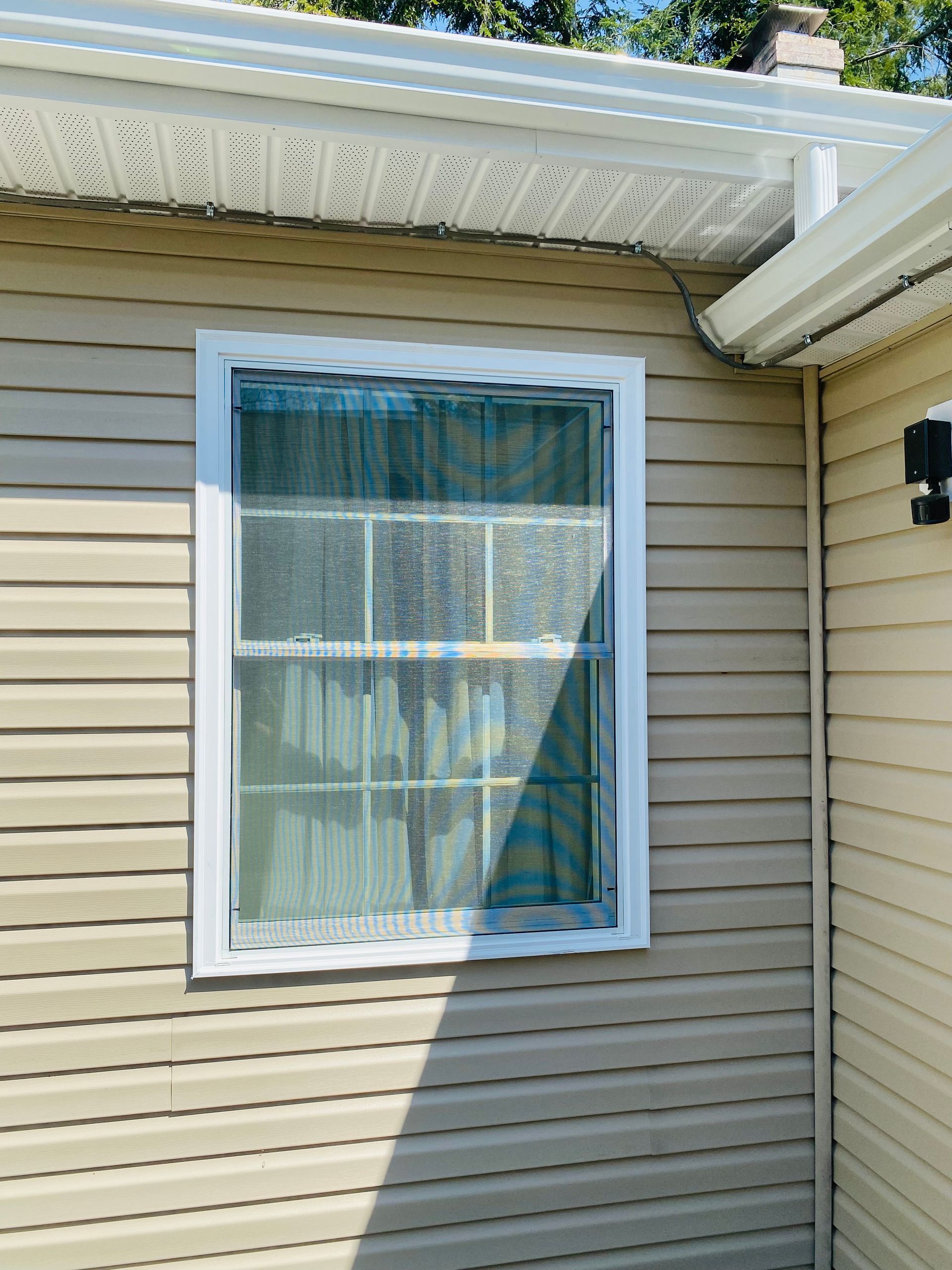 A window on the side of a house with a white frame.